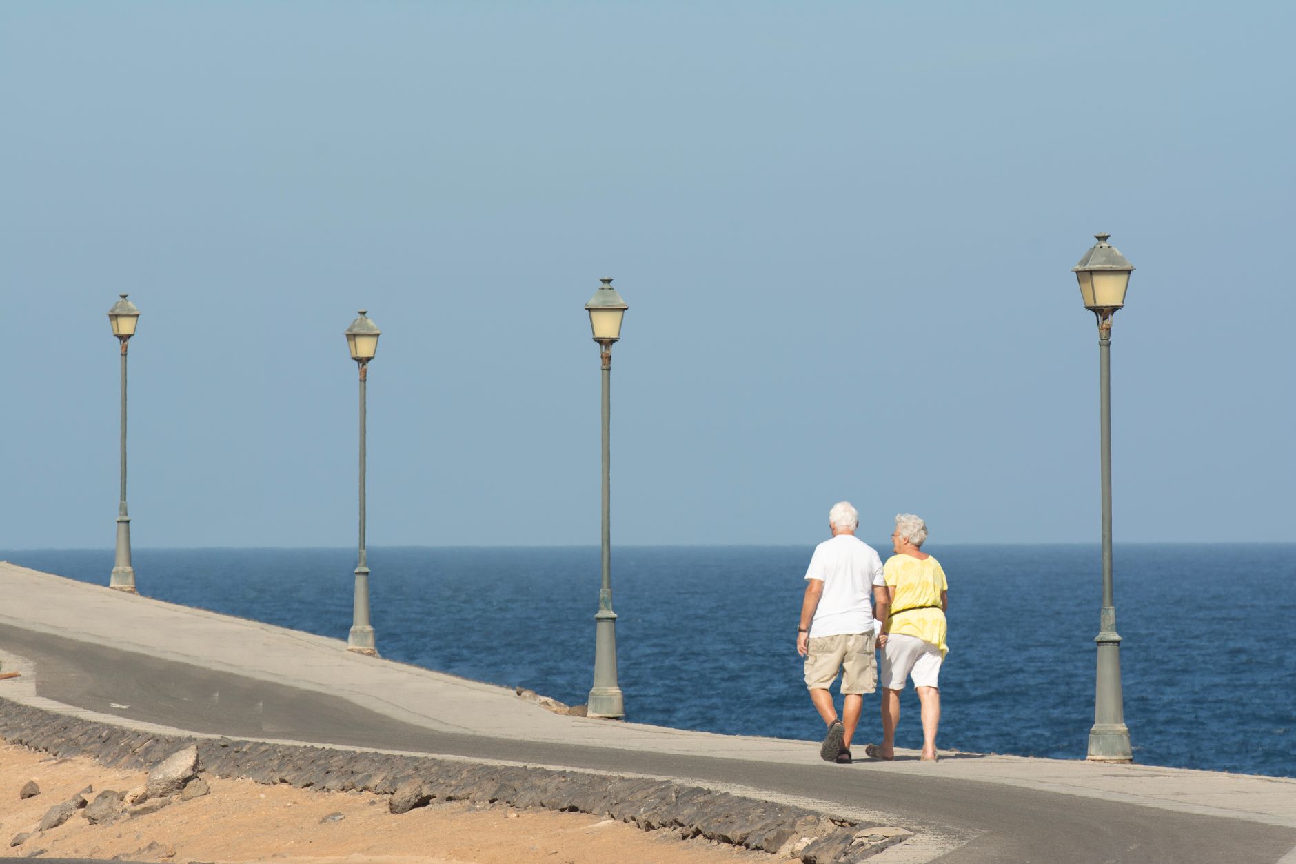 Senior couple walking on a seaside promenade enjoying a peaceful day by the ocean.